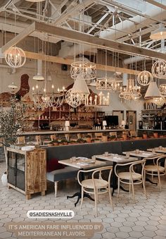 an empty restaurant with chandeliers hanging from the ceiling and tables in front of it