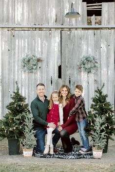 a family posing for a photo in front of their christmas tree display at the farm