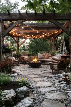 an outdoor fire pit surrounded by rocks and trees with string lights strung over the top