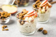 two glass bowls filled with oatmeal, apples and nuts on top of a table