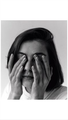 black and white photograph of a woman covering her eyes with both hands while looking at the camera