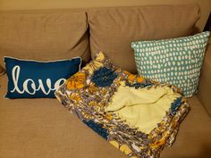 a couch with two pillows and a blanket sitting on it's side, next to a pillow that says love