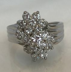 Here is an absolutely beautiful 14k white gold cluster diamond ring. This beauty is set with a total of 17 diamonds. These bright white diamonds will be causing a lot of attention! Materials: 14K White gold Stone: 1- RB .15cttw, 16- RB .80cttw Size: 8 Weight: 7.6 grams Sku: 21SB092318EVZ If you have any questions on this item, please message us! GandDJewelers.etsy.com For ring sizing, please contact us for information. Please note that all of our pieces have been analyzed & identified by a G Diamond Cluster Ring In Fine Jewelry Style, Diamond White Cluster Diamond Ring, Dazzling Diamond Cluster Ring With Single Cut Diamonds, Dazzling Cluster Diamond Ring With Single Cut Diamonds, Sparkling Cluster Diamond Ring, Dazzling Silver Diamond Ring In Cluster Shape, Fine Jewelry Diamond Ring With Single Cut Cluster, Dazzling Silver Diamond Ring With Cluster Shape, Dazzling Silver Cluster Diamond Ring