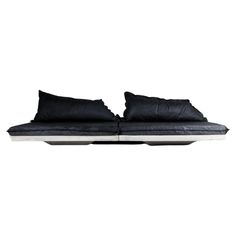 a black leather couch with two pillows on it's back and the seat folded down