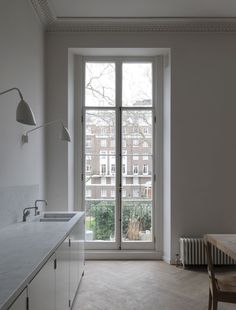 an empty kitchen and dining room with white walls, flooring and large windows looking out onto the city