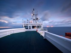 the deck of a cruise ship at dusk with clouds in the sky over the ocean