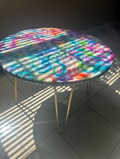 a table that has been painted with different colors and shapes on it, sitting on a tile floor