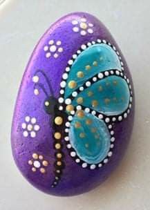 a purple and blue painted rock sitting on top of a table