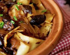 a close up of a bowl of food with onions and olives on a table