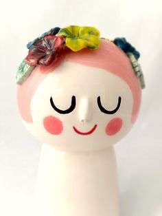 a ceramic doll with a flower in her hair and eyes closed on a white surface