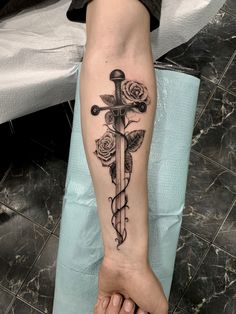 a person with a tattoo on their arm holding a cross and roses in the background