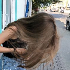 a woman with her hair blowing in the wind on a wooden deck next to a parked car