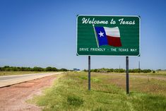 a welcome to texas sign on the side of the road with a blue sky in the background