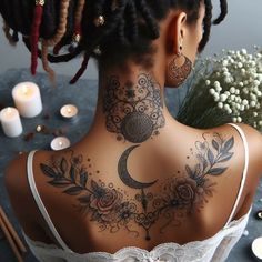 the back of a woman's neck with tattoos on it and candles around her