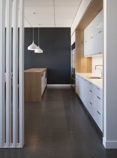 an empty kitchen with black walls and white cabinets is seen from the hallway to the dining room