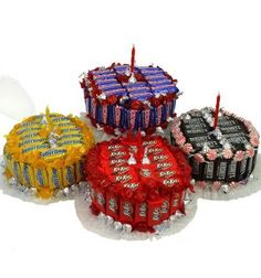 four cakes with candy bars on top and one cake covered in foil wrappers