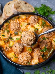 meatball soup in a black bowl with a ladle scooping from the top