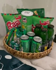 a basket filled with lots of green sodas and snacks on top of a bed