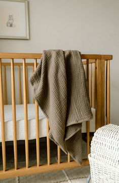 a baby crib with a blanket on top of it and a white chair in the background