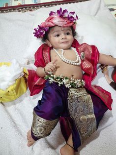 a baby dressed up like a princess laying on top of a bed