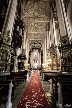 the inside of a church with red carpet and white flowers on the aisle leading up to the alter