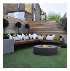 an outdoor fire pit surrounded by wooden benches and seating on the grass in front of a building