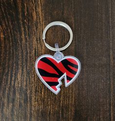 a red and black heart shaped keychain sitting on top of a wooden table