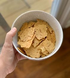 a hand holding a white bowl filled with cereal