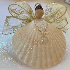 a glass angel ornament sitting on top of a white plate with glitters