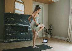 a woman standing on a yoga mat in front of a fireplace