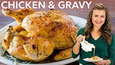 a woman holding a plate with chicken and gravy on it, in front of a turkey