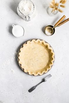 an uncooked pie sitting on top of a table next to utensils