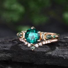 a green ring with diamonds on top of a piece of wood in front of some leaves