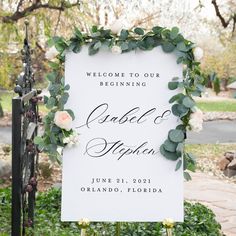 a welcome sign with flowers and greenery on it