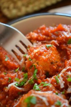 a bowl filled with meatballs covered in sauce and parmesan cheese