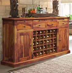 a wooden buffet table with wine bottles on it and an ornate mirror above the cabinet