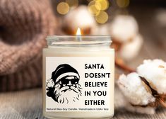 santa doesn't believe in you either candle with cotton on the table next to it