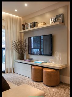 a living room filled with furniture and a flat screen tv mounted on a wall next to a window