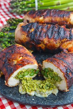 a plate topped with meat and veggies covered in pesto next to asparagus