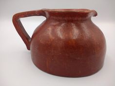 an old brown pitcher is sitting on a white surface