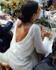 two people sitting at a table with food and drinks in front of them, looking off into the distance