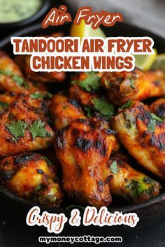 an air fryer with chicken wings and cilantro on the side, next to some dipping sauces