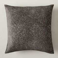 a black and white pillow with small dots on the front, sitting against a wall