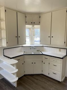 an empty kitchen with white cabinets and black counter tops in the middle of the room