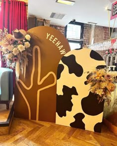 two large cow heads are on display in a room with wooden floors and red curtains