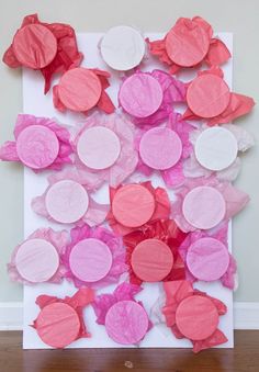 a paper plate collage with pink and white circles on it, sitting on a wooden floor