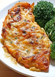 a white plate topped with chicken and broccoli on top of a wooden table