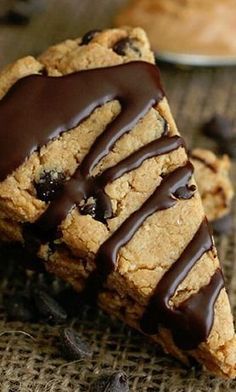 two cookies with chocolate drizzled on them sitting next to each other and one half eaten