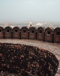 an old stone structure with many windows on the top of it and foggy sky in the background