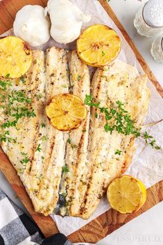 grilled fish with lemons and garlic on a cutting board